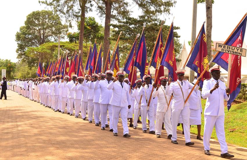 Salvationists in white uniforms march down the road