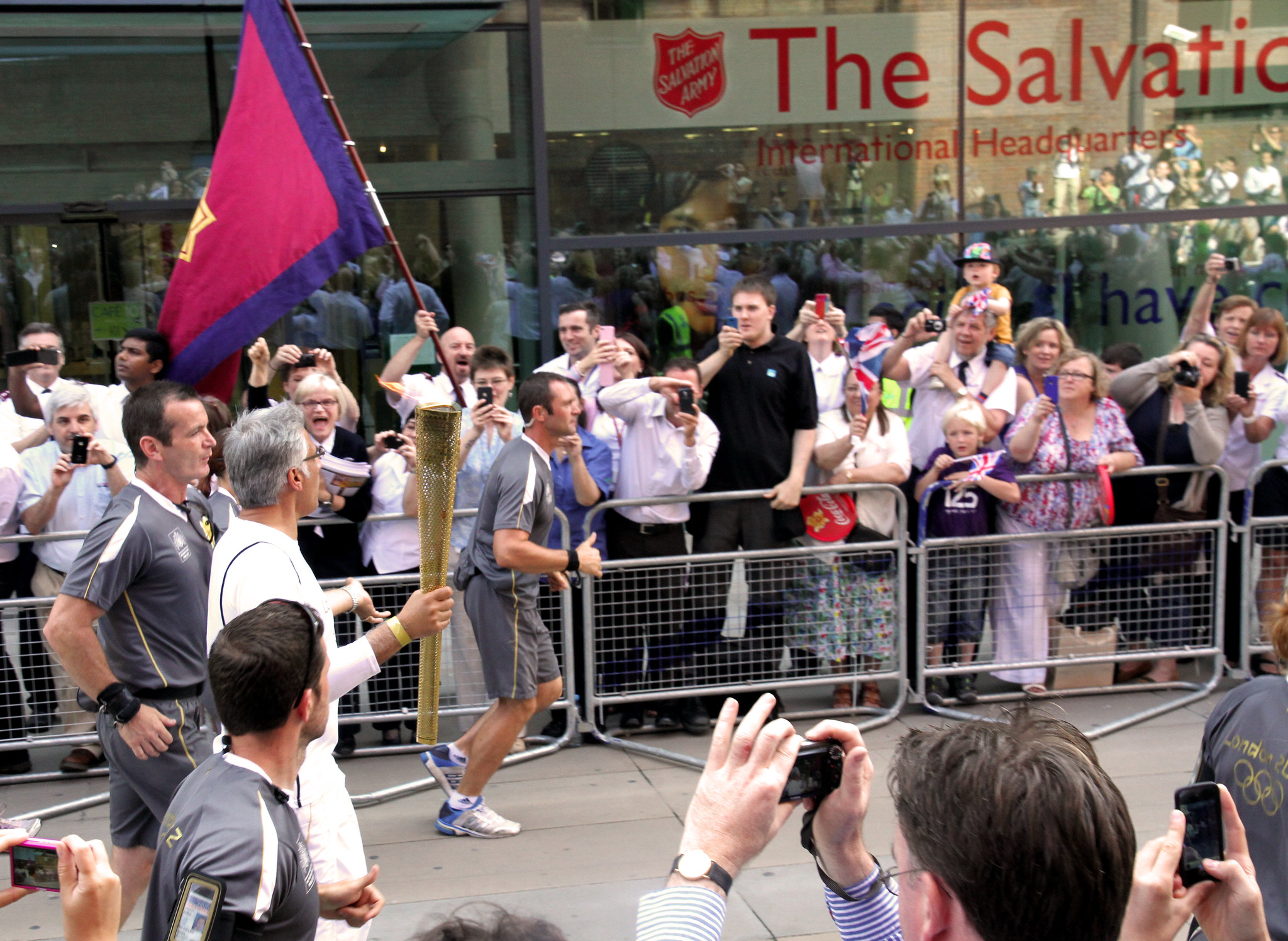 A runner carries the Olympic torch past IHQ