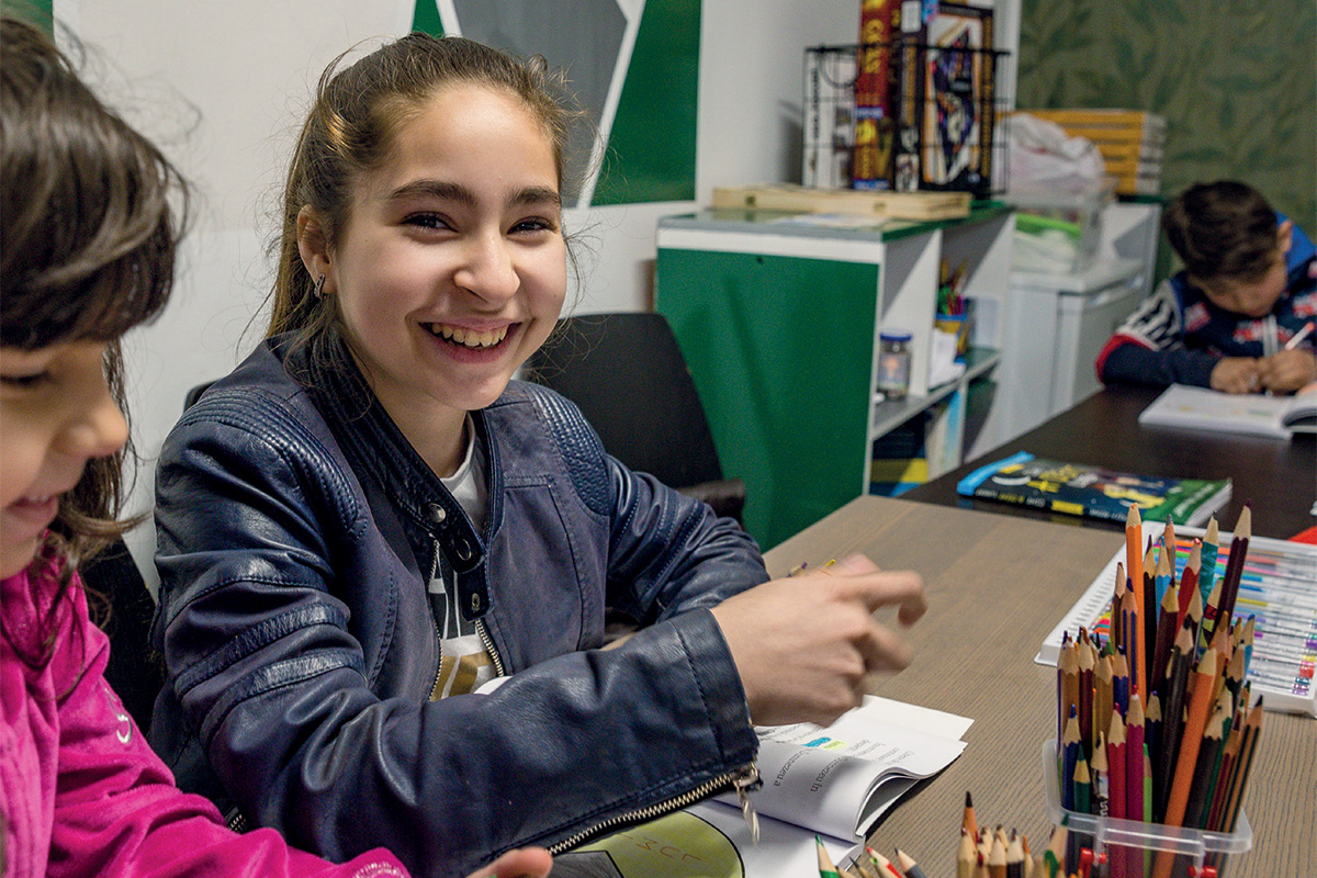 A girl smiles at the camera as she takes part in a homework club
