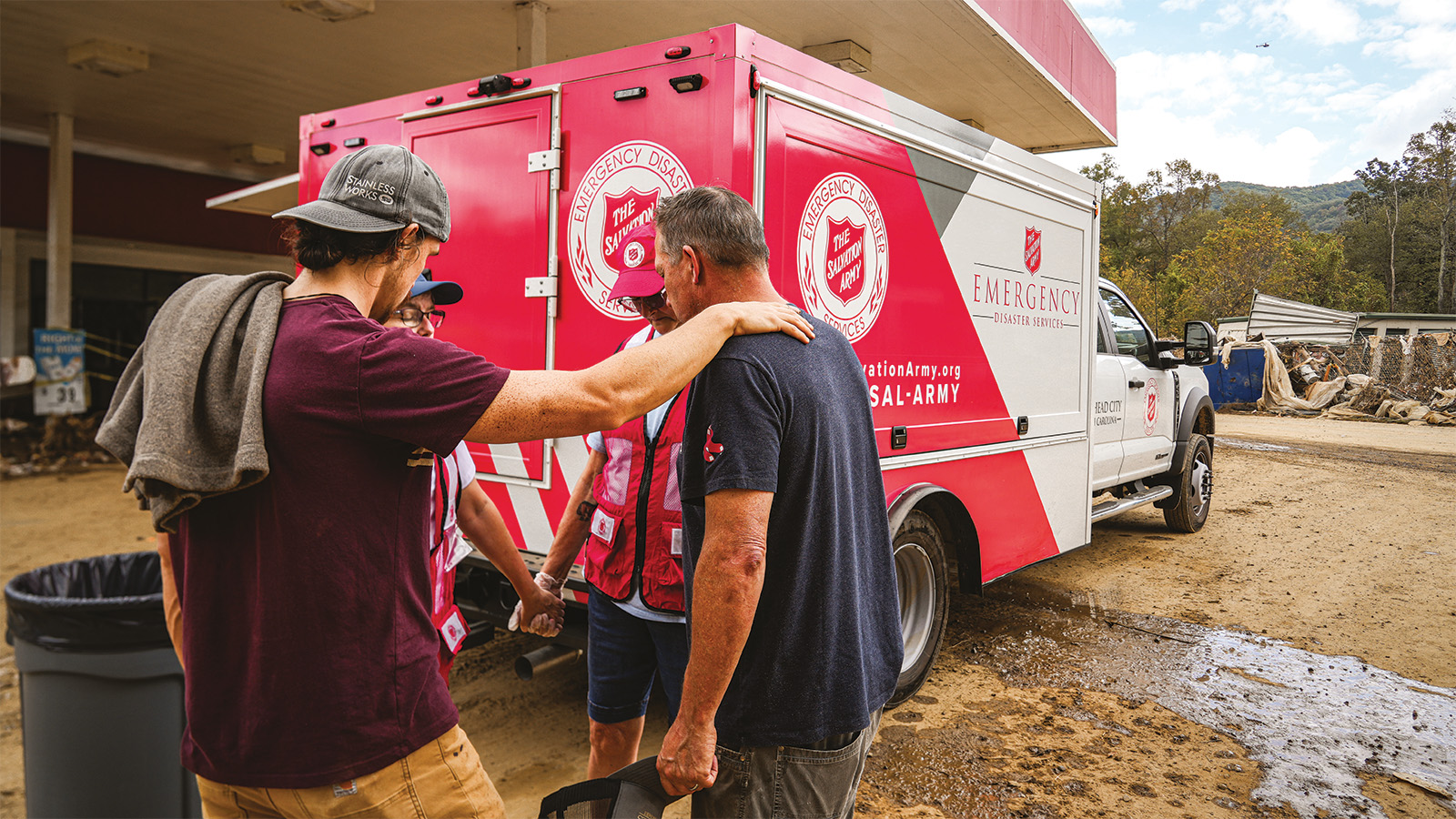 An emergency response team prayers in front of a Salvation Army emergency vehicle
