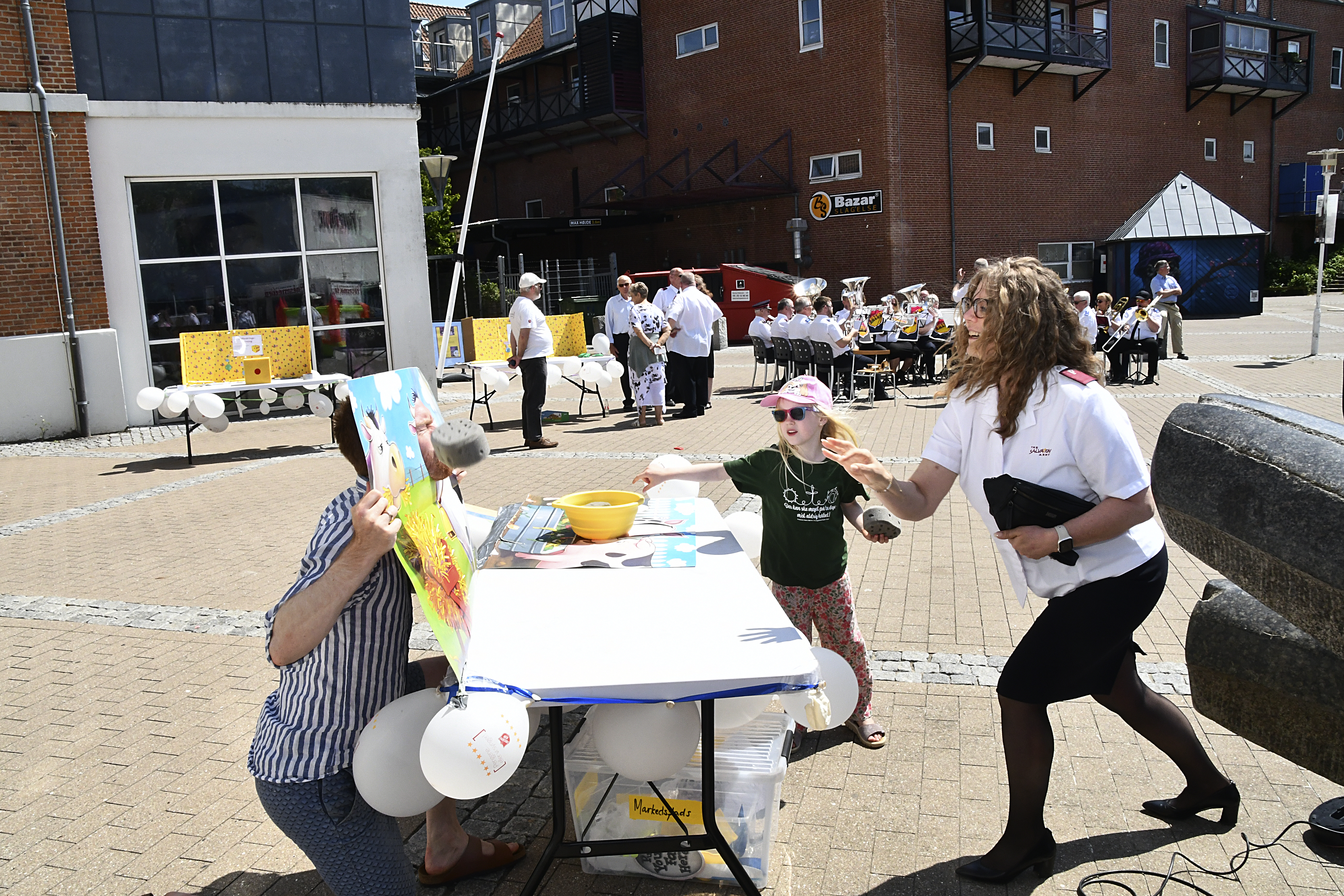 A girl and a woman in Salvation Army uniform throw sponges at a man posing