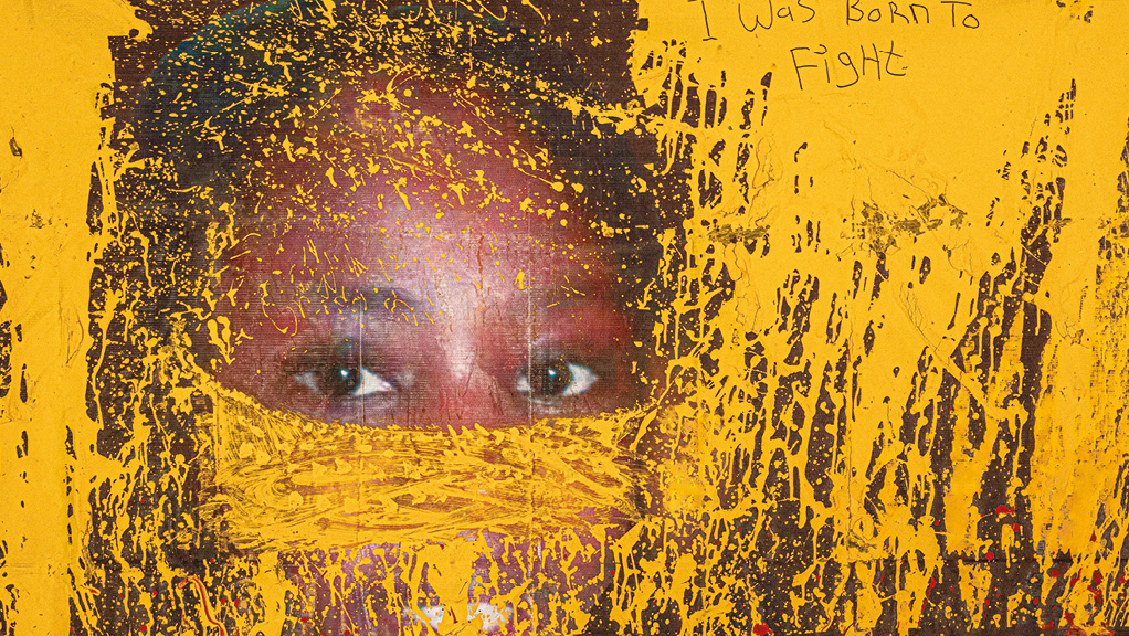 A face partially obscured by yellow paint, with the text 'I was born to fight'