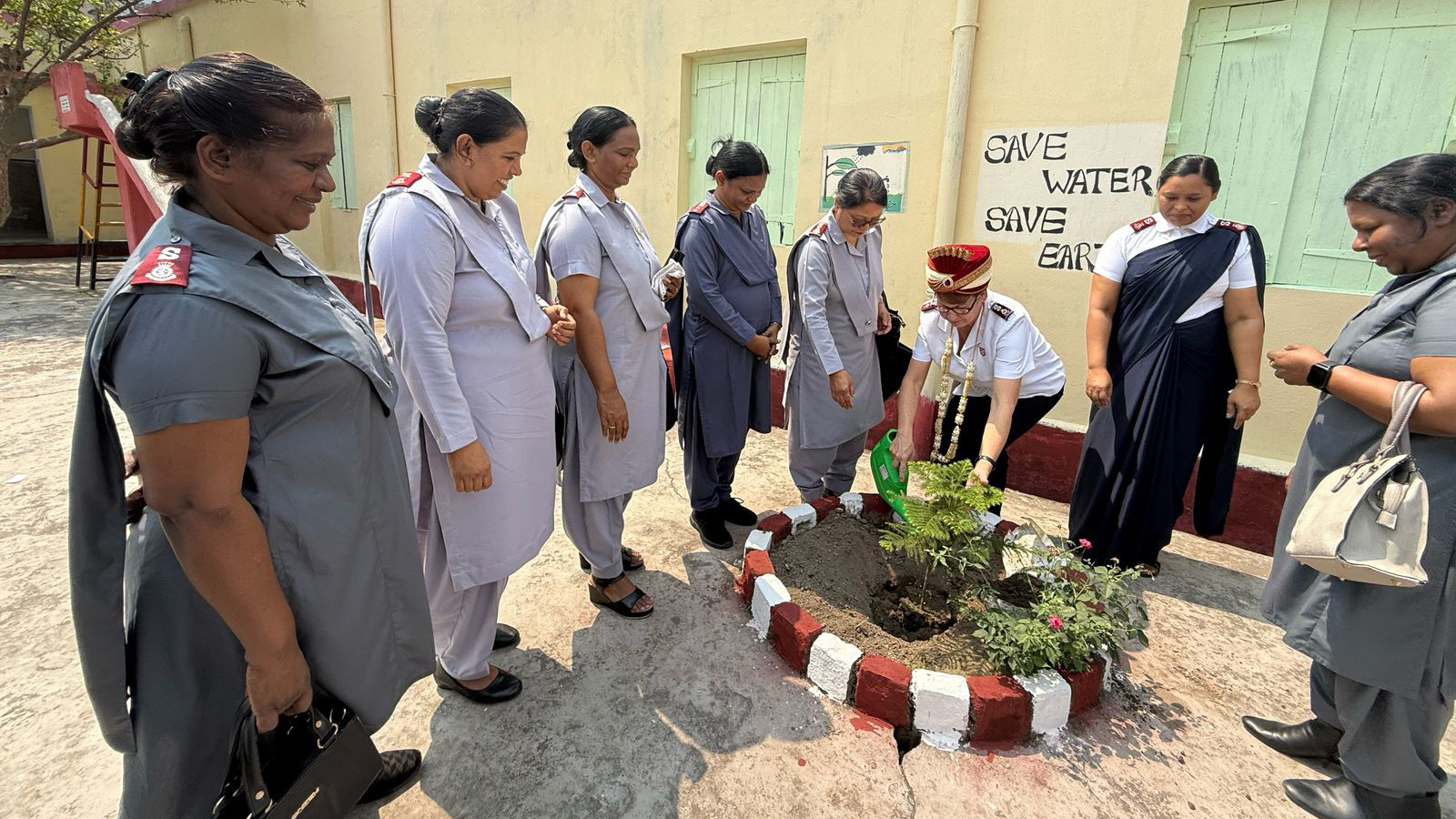Commissioner Shelley Hill waters a newly planted tree surrounded by women in Salvation Army uniform