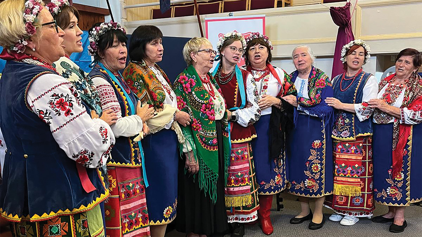 A group of women sing in traditional Ukrainian dresses