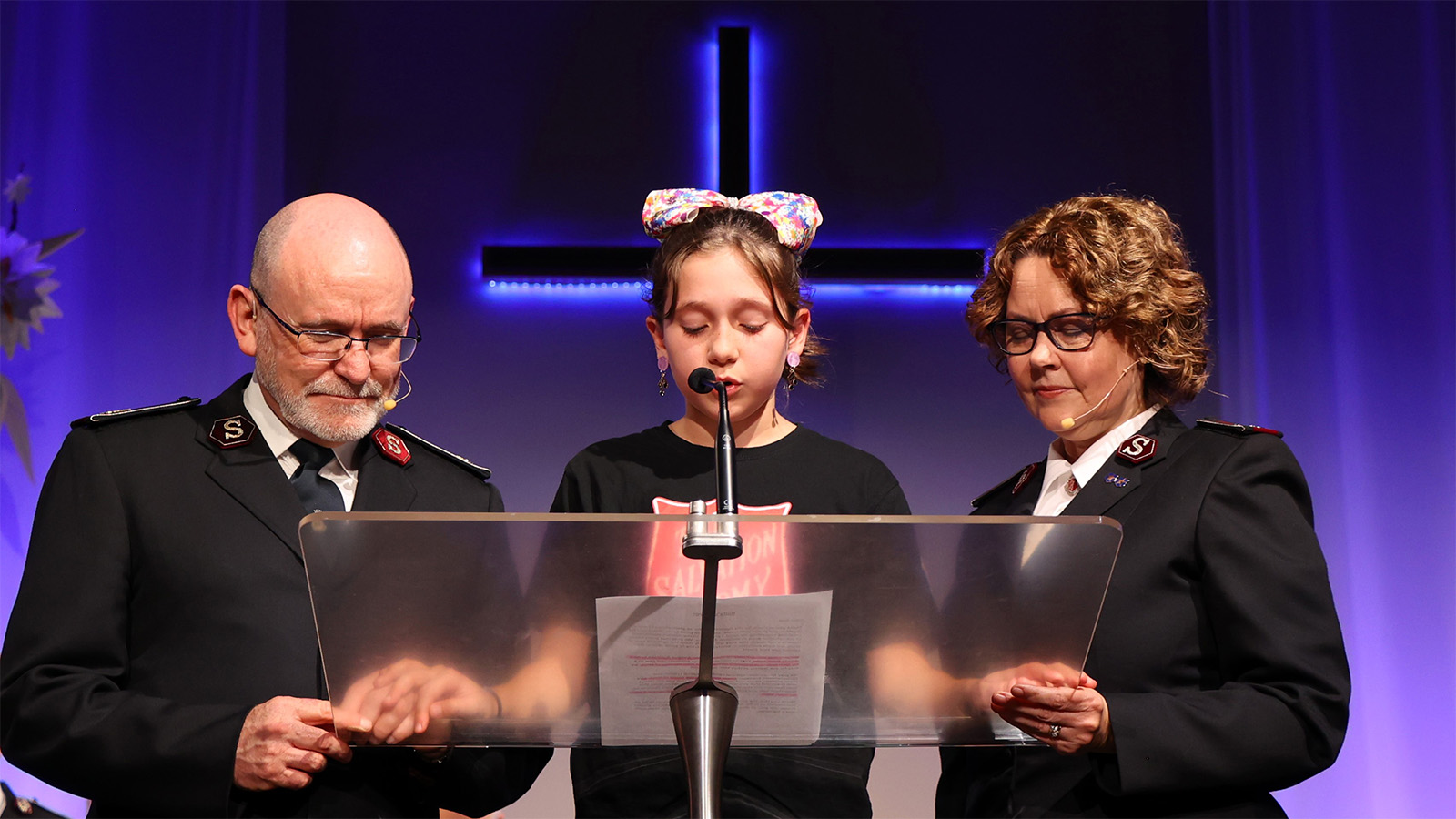 General Lyndon and Commissioner Bronwyn Buckingham stand with Bella, 11, as she prays during the Western Australia Division rally in Perth (Photo: Peter Mazanec)