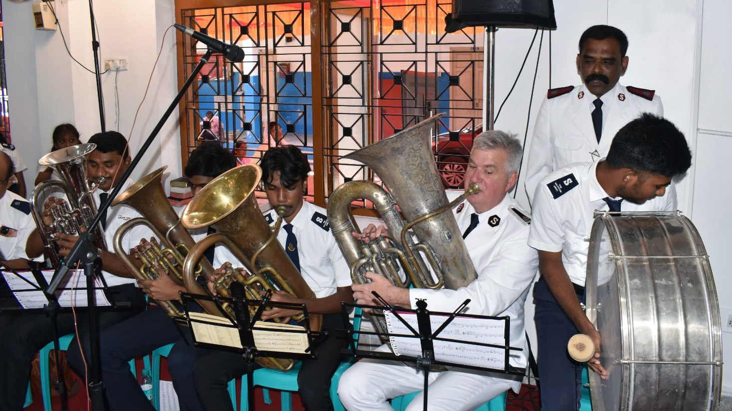 The Chief of the Staff plays the tuba alongside members of the corps playing brass instruments and a drum