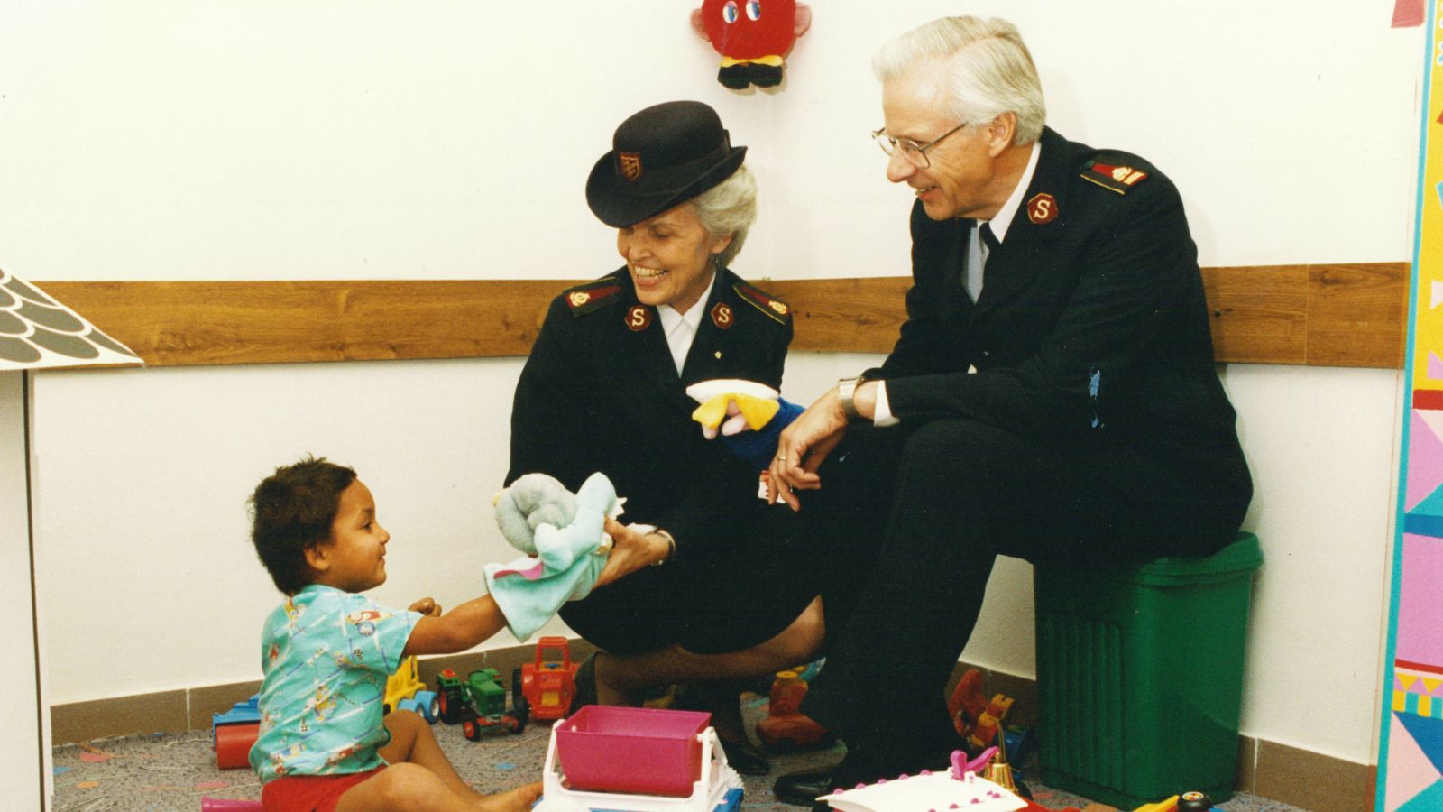 General Rader (Rtd) and Commissioner Kay Rader sit surrounded by toys as they speak to a young child