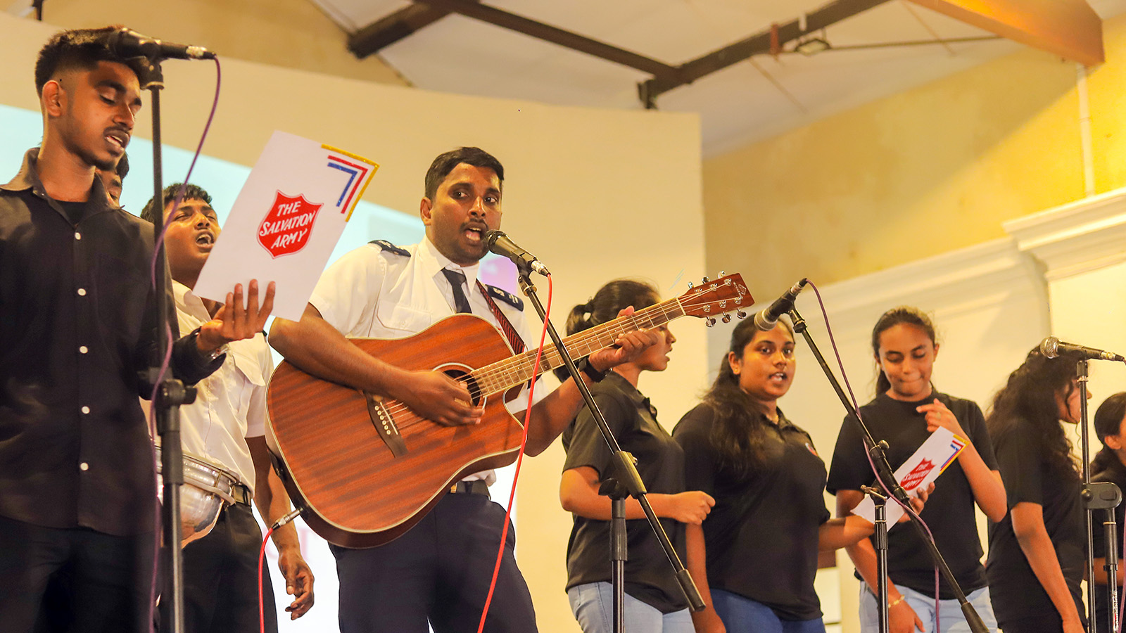 Young men and women lead worship with a guitar