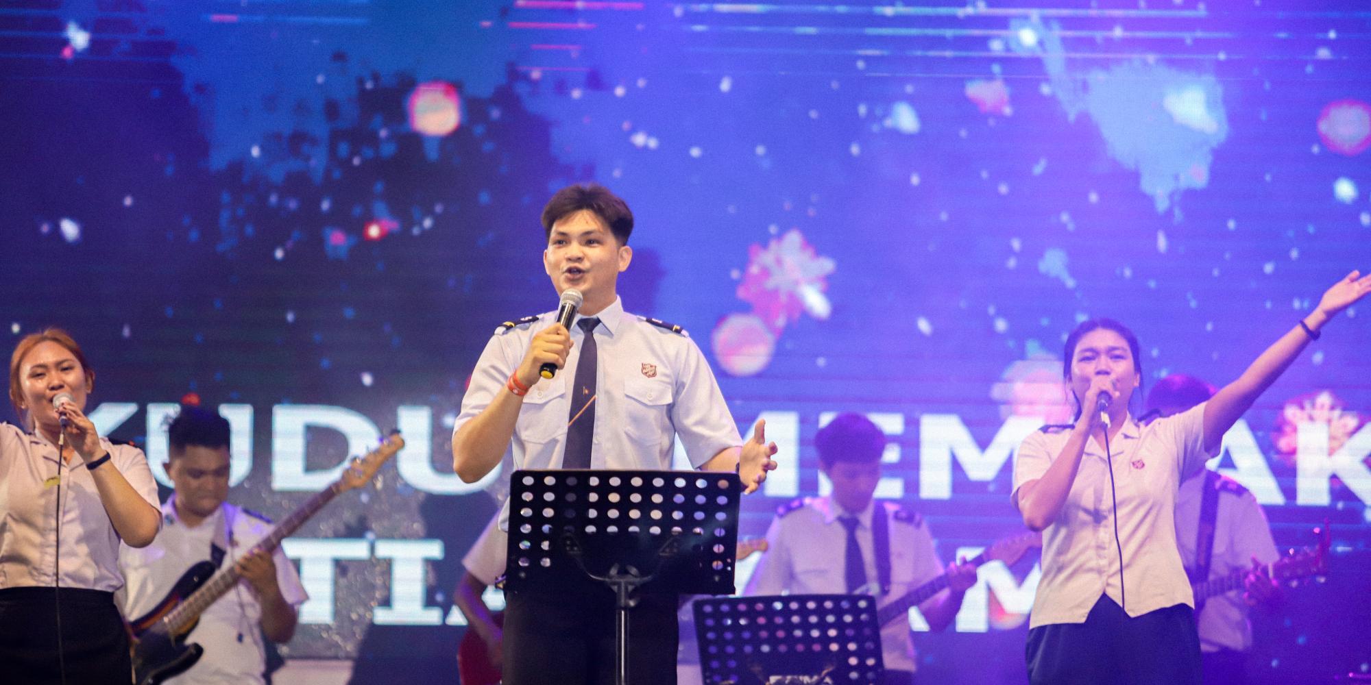 Young people in Salvation Army uniform sing into microphones