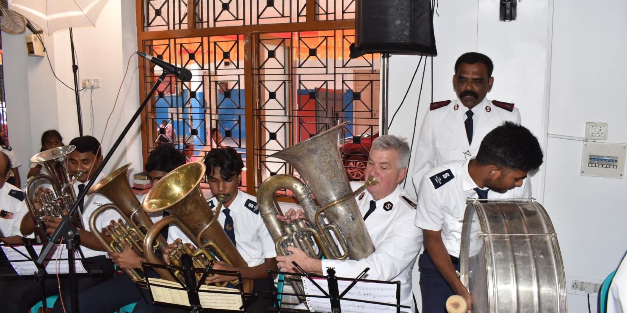 The Chief of the Staff plays the tuba alongside members of the corps playing brass instruments and a drum
