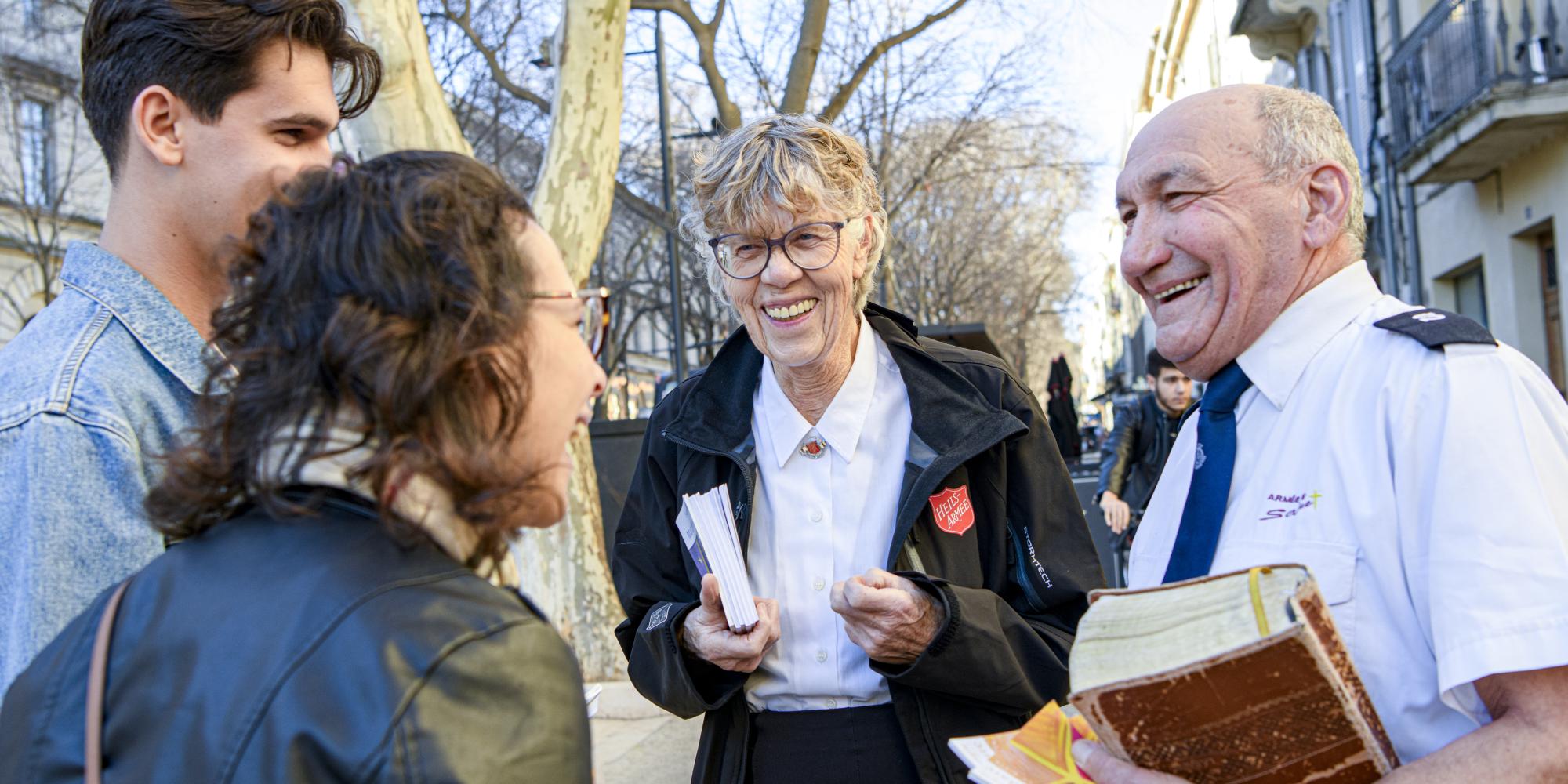 A woman and a man in Salvation Army uniform speak to people on the street