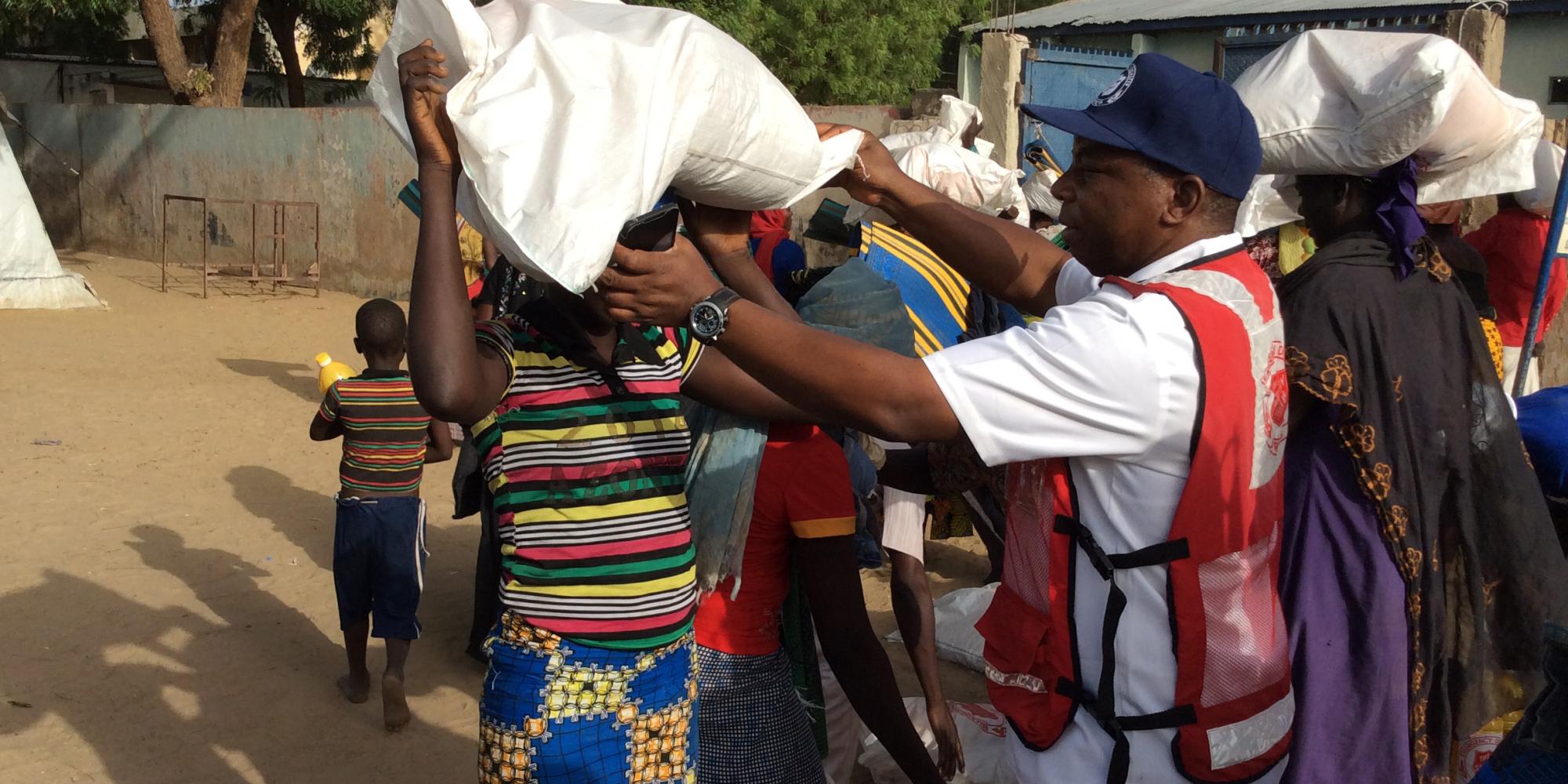 A man wearing a Salvation Army jacket helps a woman with a bag of supplies