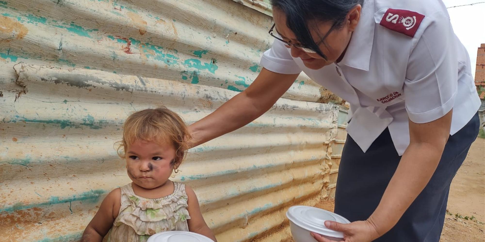 A woman in Salvation Army uniform speaks to a young child