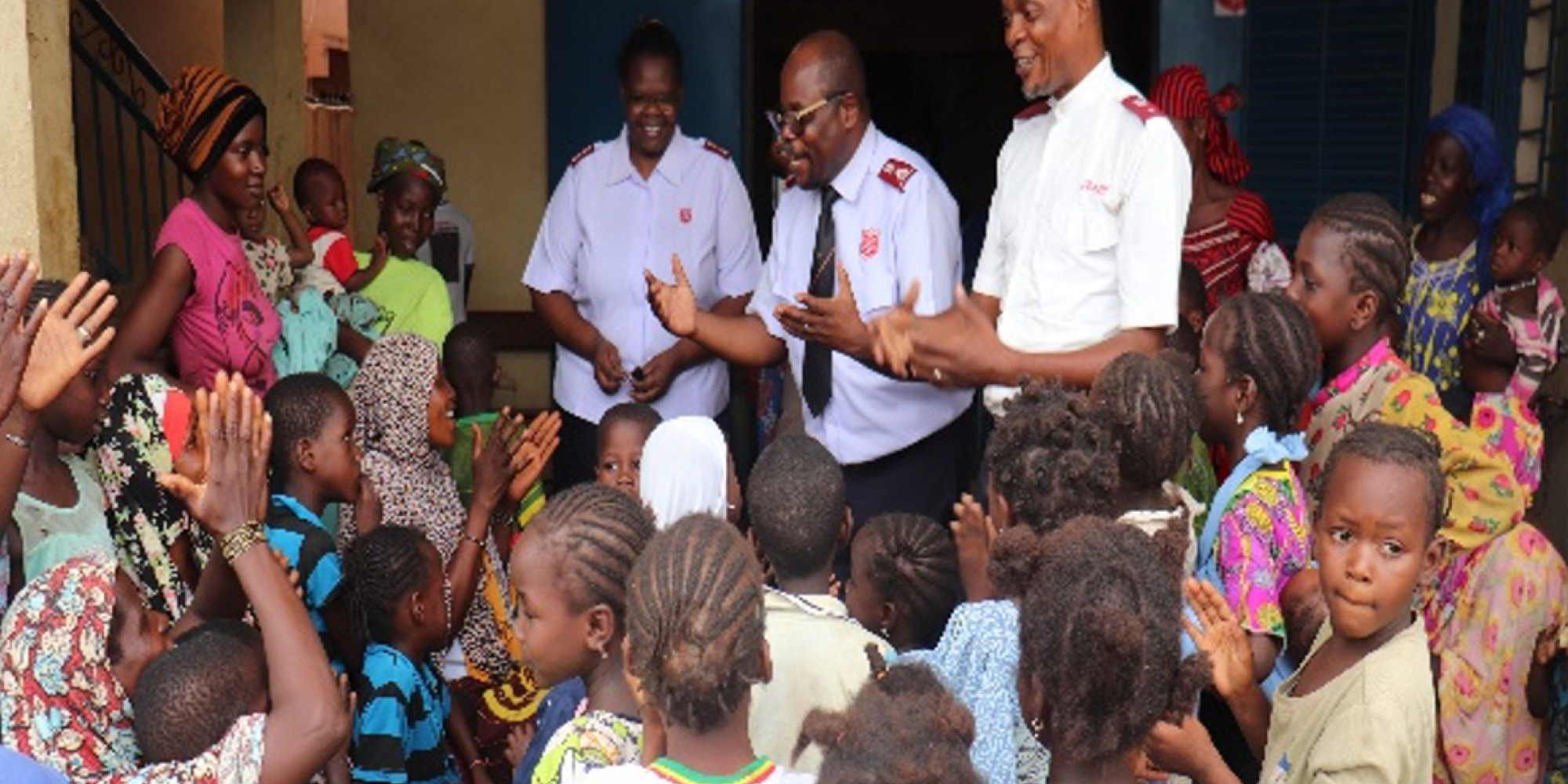 Salvation Army officers speak to a crowd of women and children