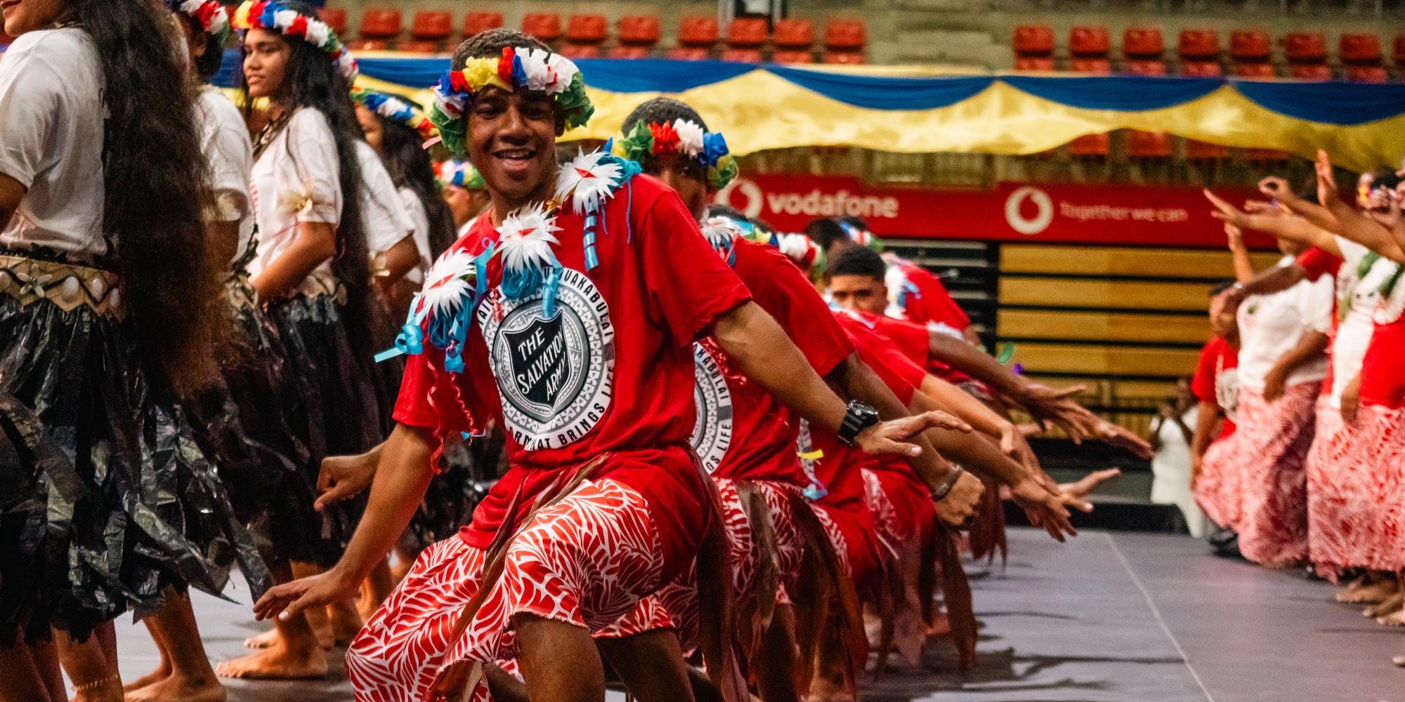 Performers wearing flower headdresses and Salvation Army t-shirts
