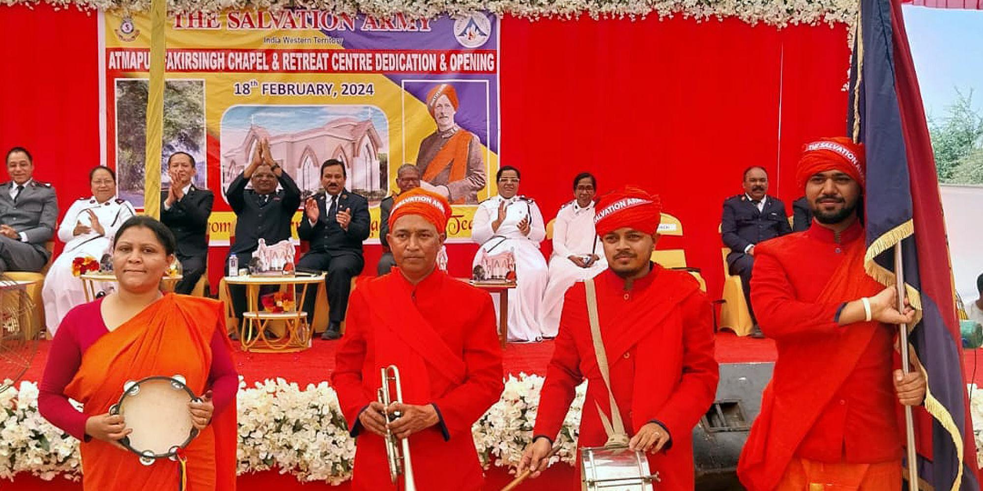 A group wearing red hold a timbrel, a trumpet, a drum and a Salvation Army flag
