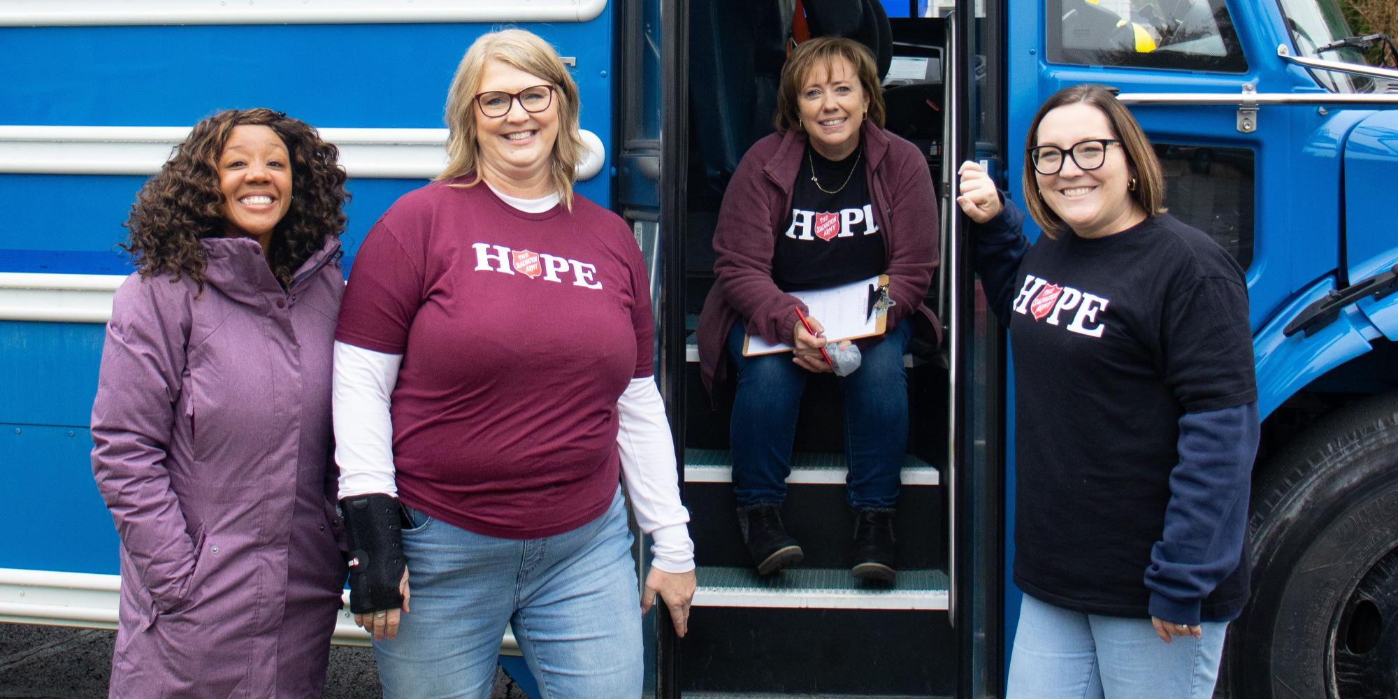 Women wearing Salvation Army t-shirts in front of a bus