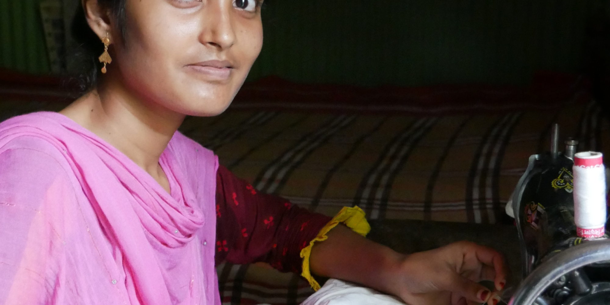 A woman sits at a sewing maching