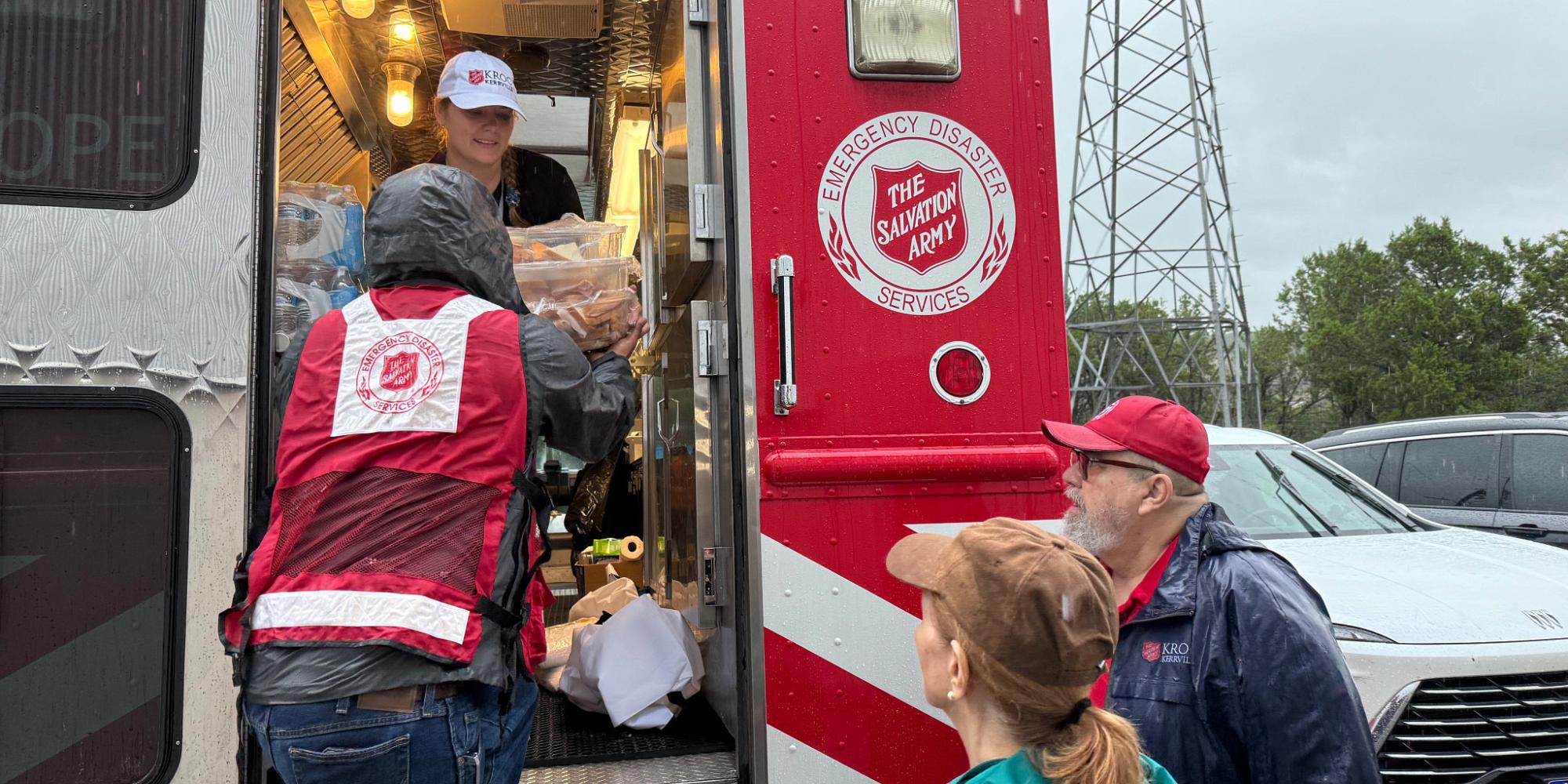 Volunteers unload supplies from a Salvation Army emergency vehicle