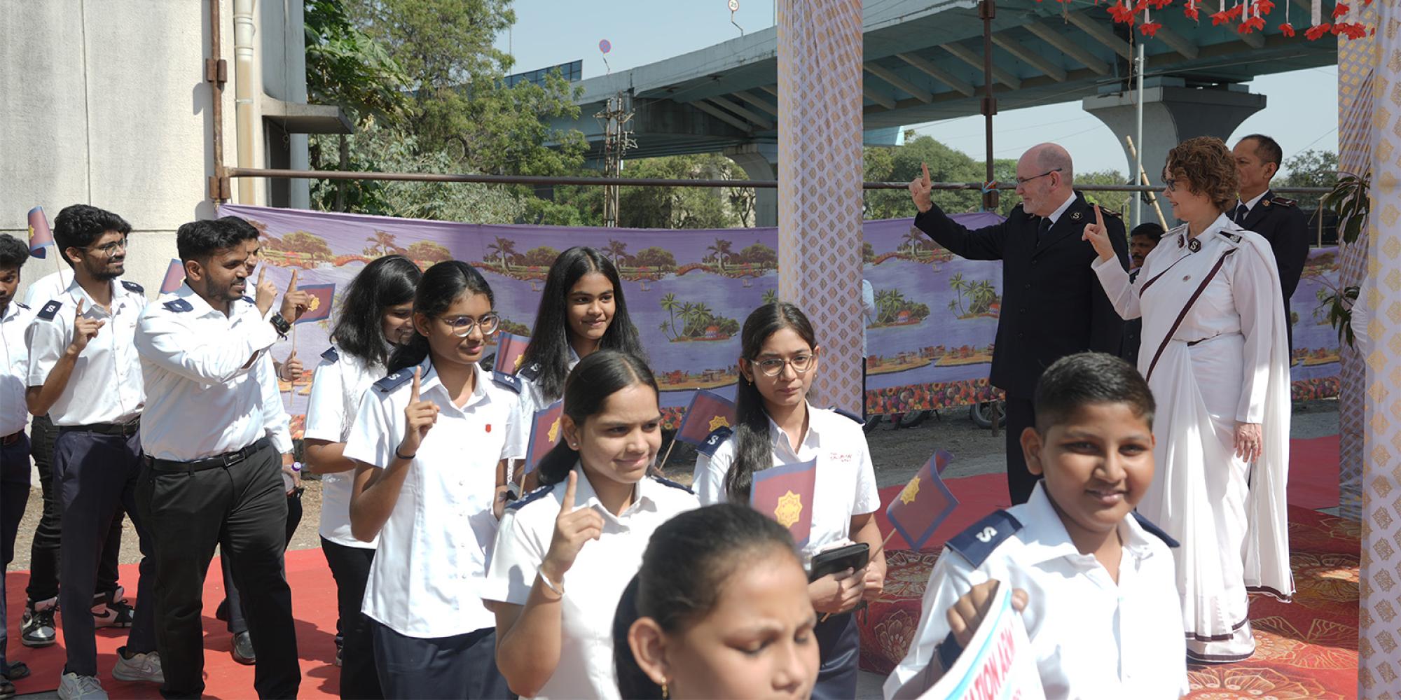Young people in India salute as they march past the international leaders