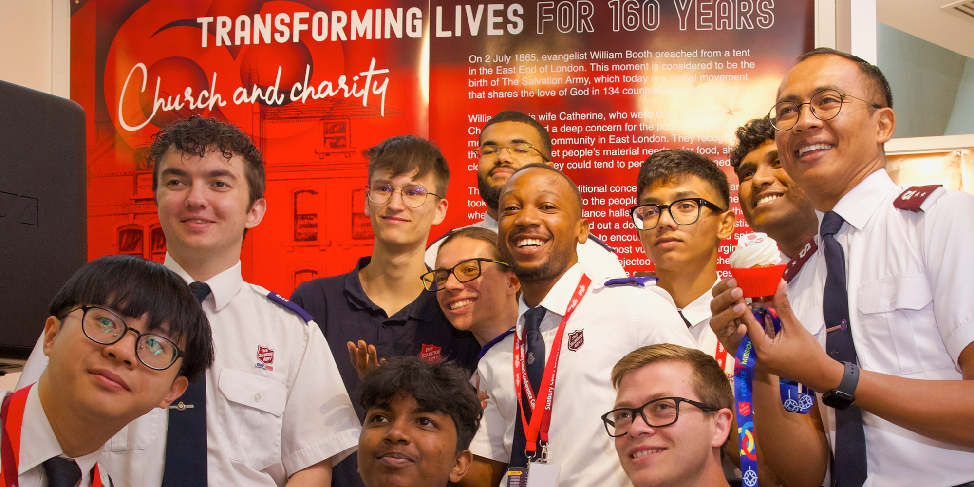 A group of the international Children and Young People Advisory group in front of the exhibition 'Transforming lives for 160 years'