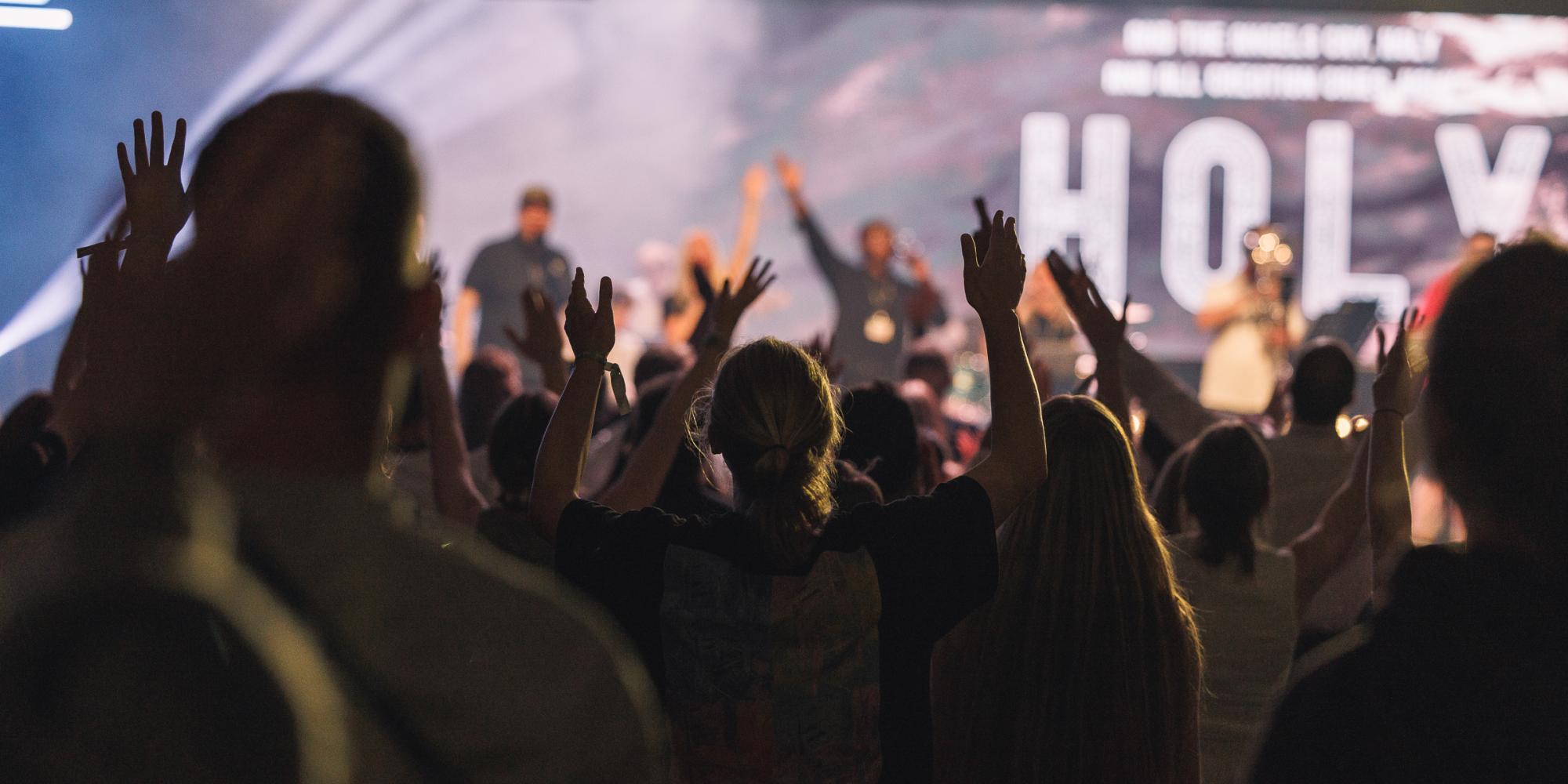 Young people raise their hands in worship