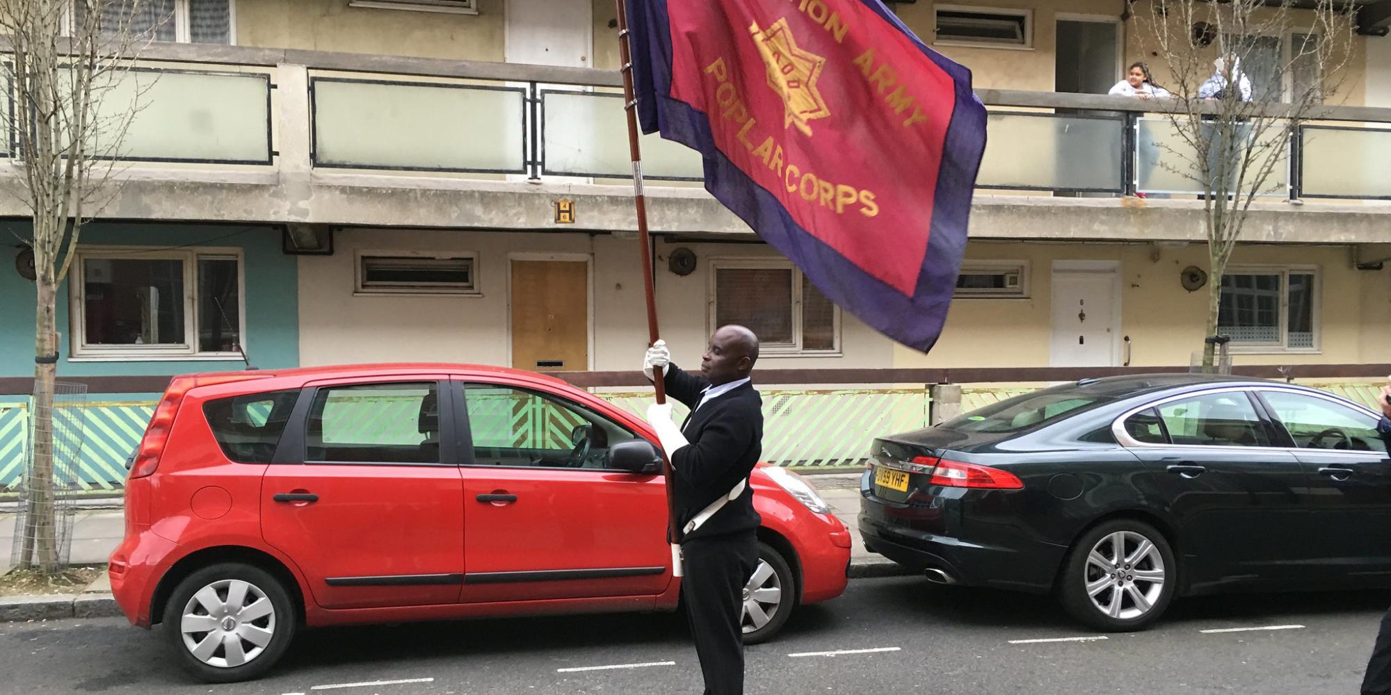 A Salvation Army soldier holds a corps flag aloft