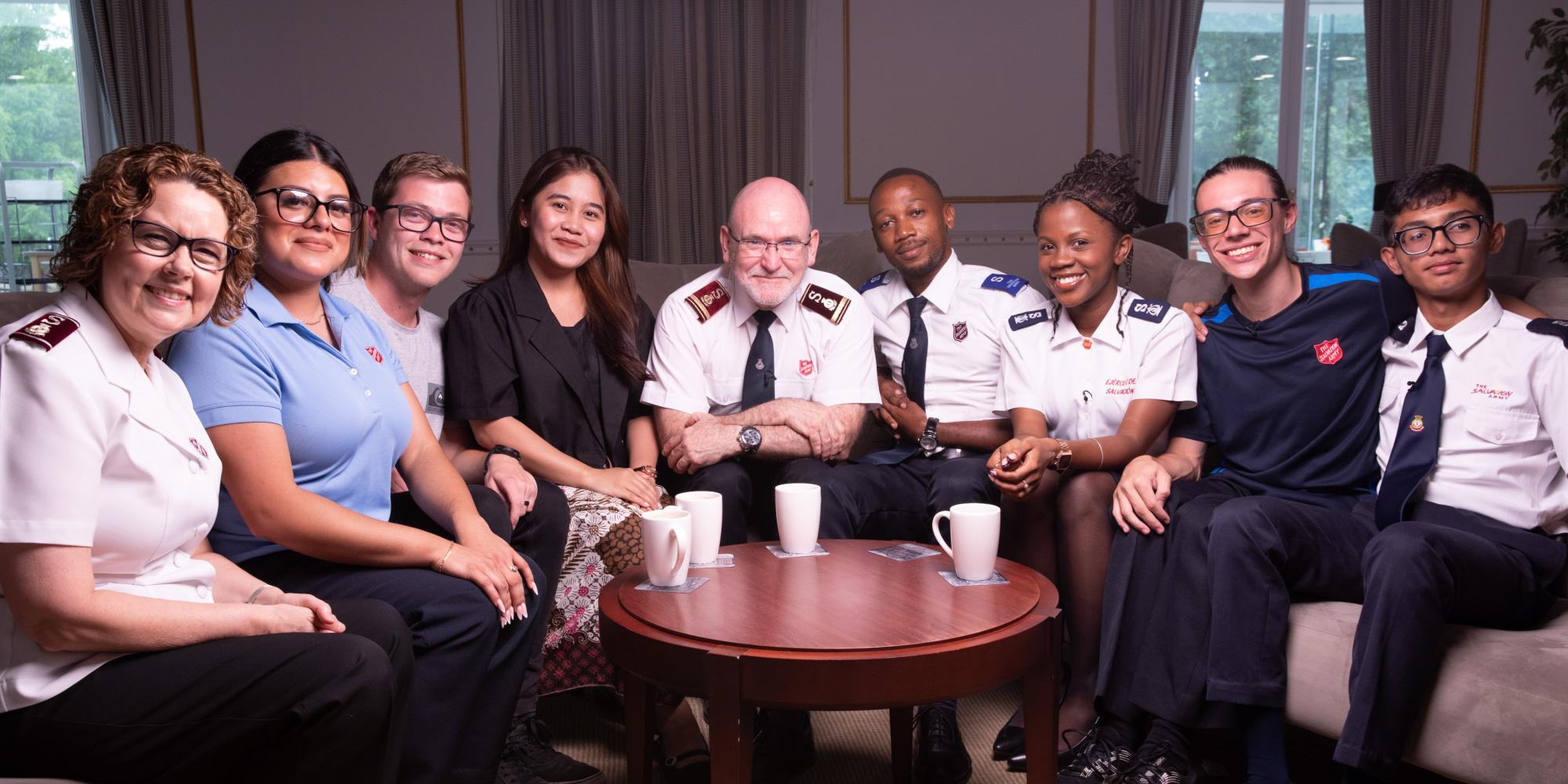 The international leaders sit around a coffee table with young Salvation Army members