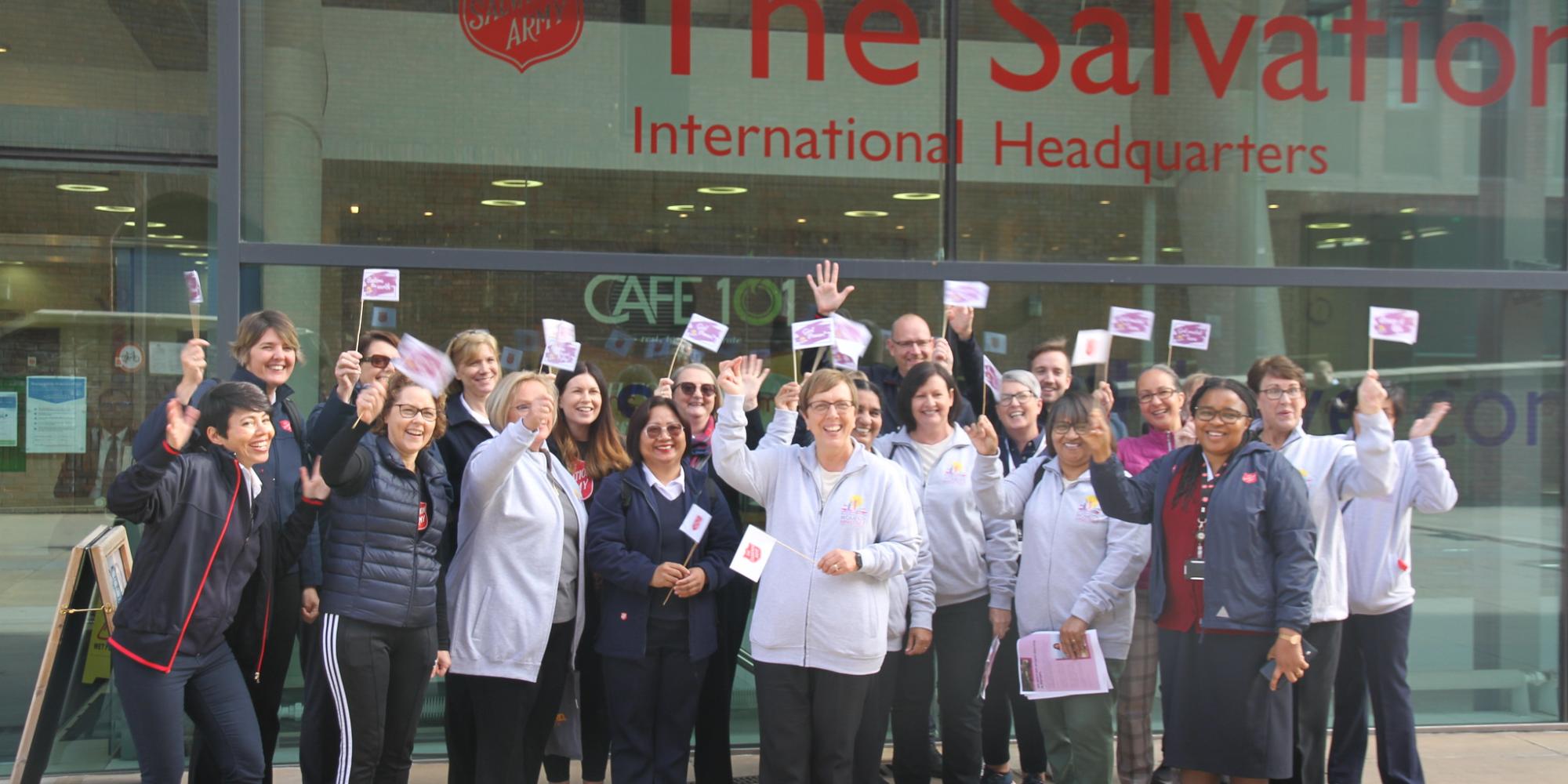 A group of women wave flags outside the IHQ building