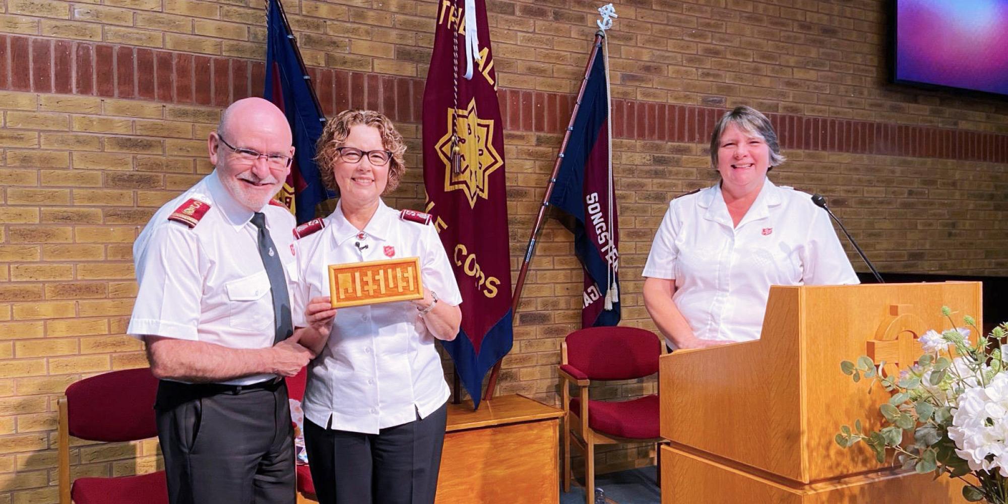 General Lyndon and Commissioner Bronwyn, pictured with corps officer Captain Jacqueline Coates, are gifted a 'Jesus board' during their visit to Dunstable