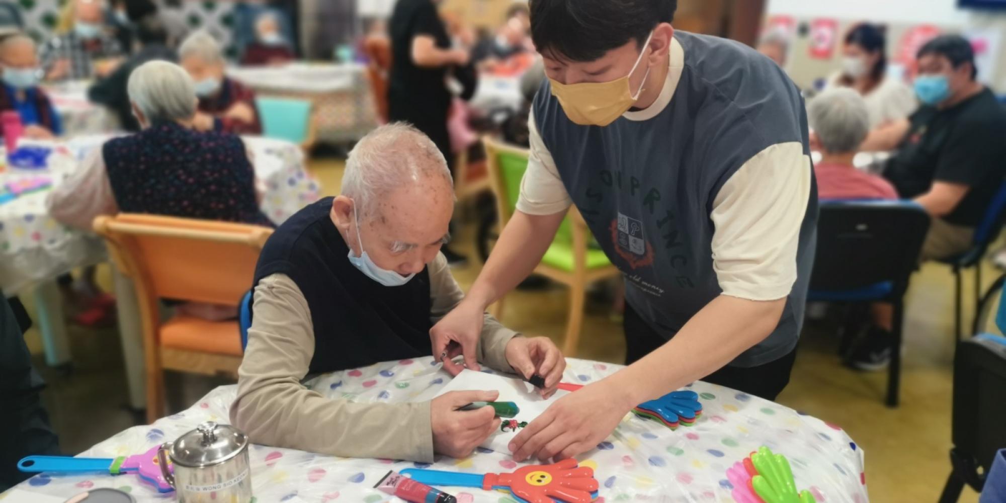 A carer assists a male resident in a care facility in Macau