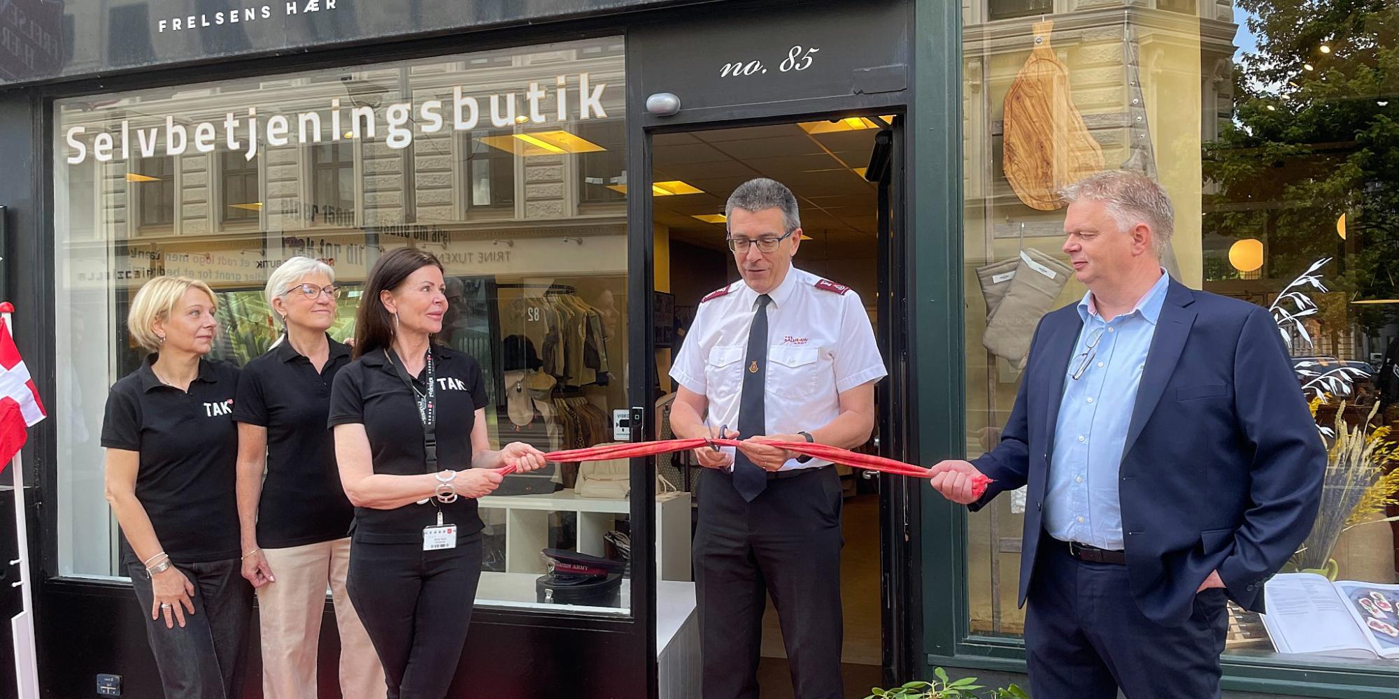 A Salvation Army officer cuts the ribbon in front on the shop