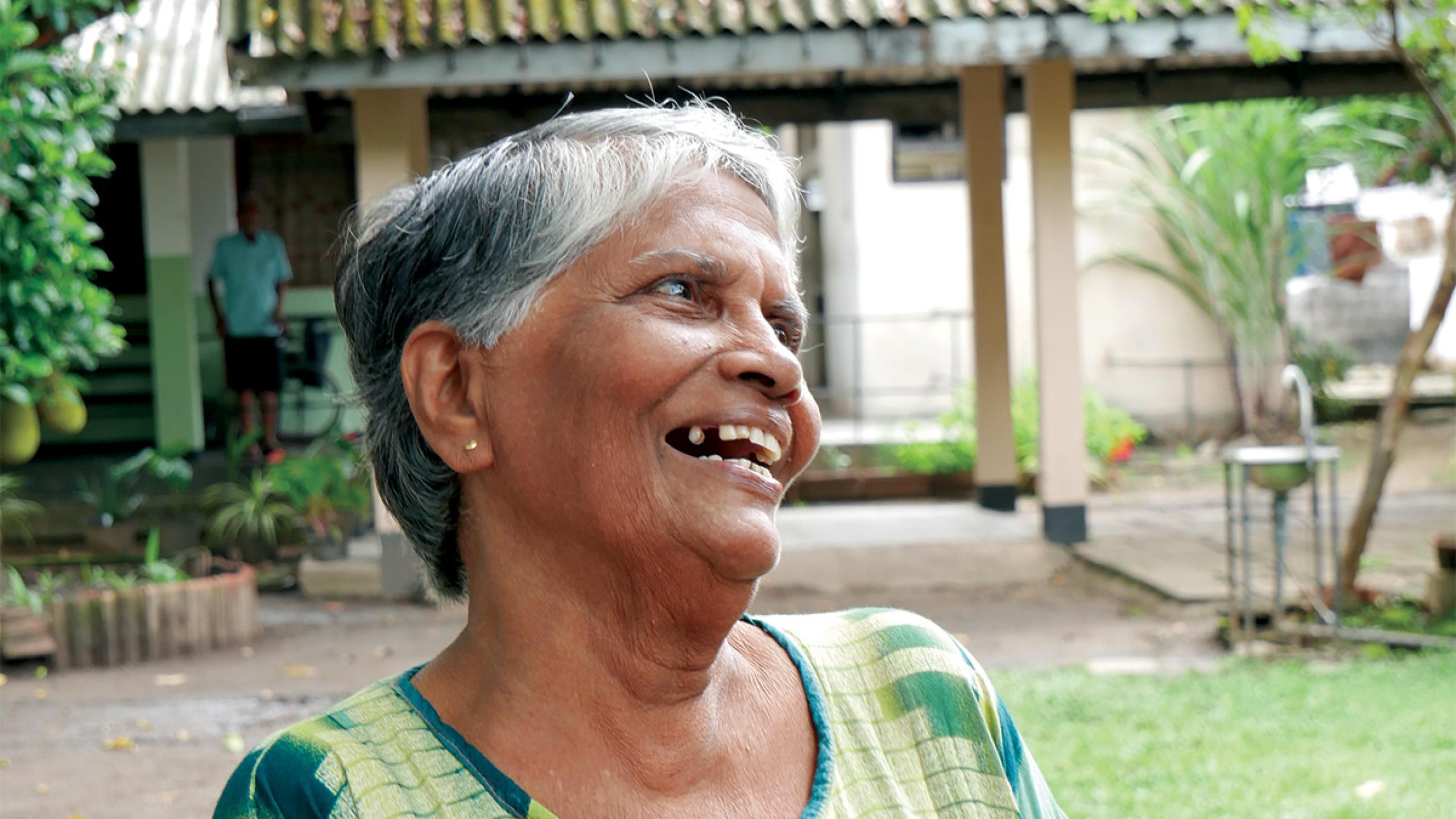An older woman smiles at someone off-camera
