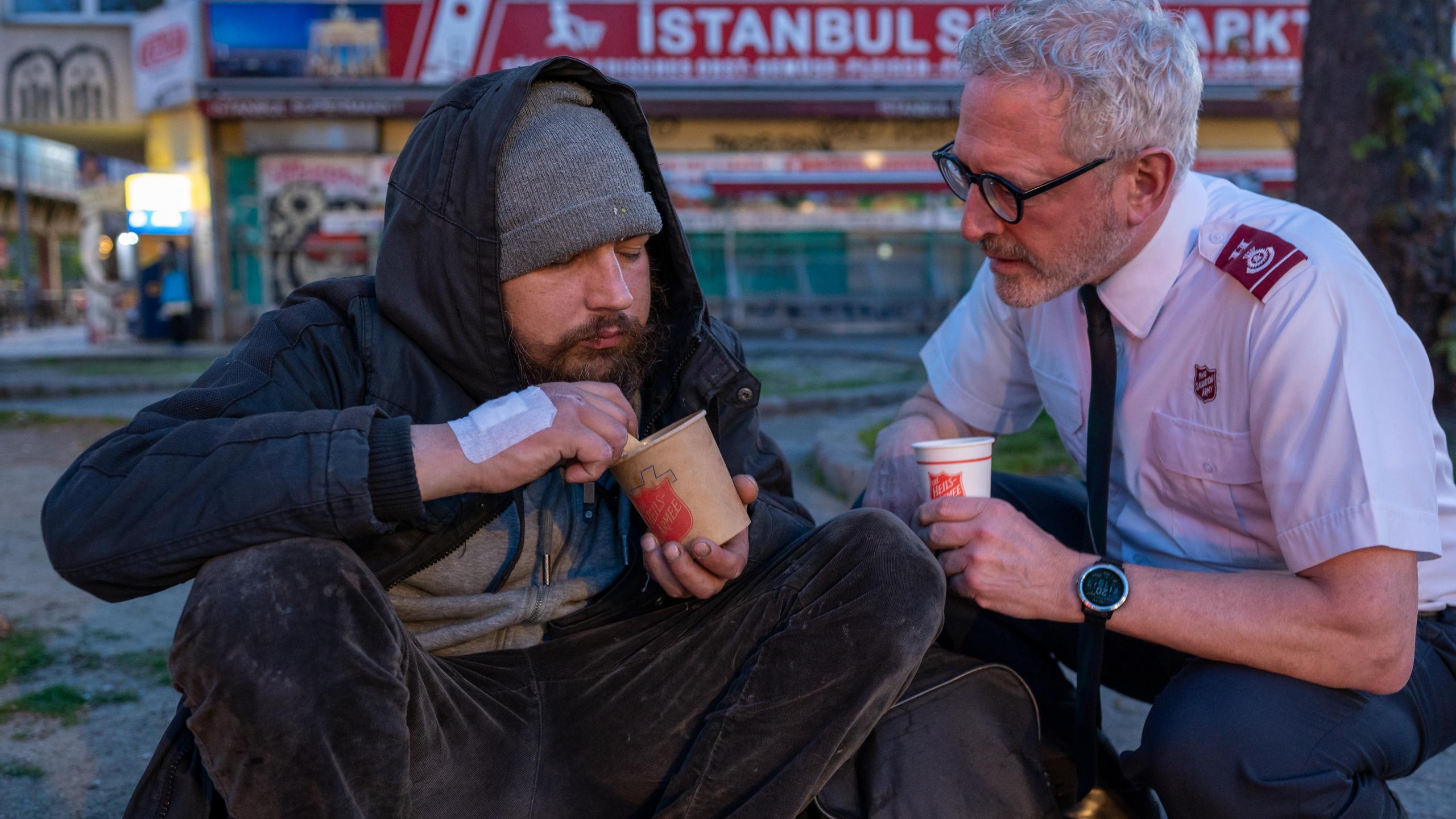A man in Salvation Army uniform talks to a man on the street