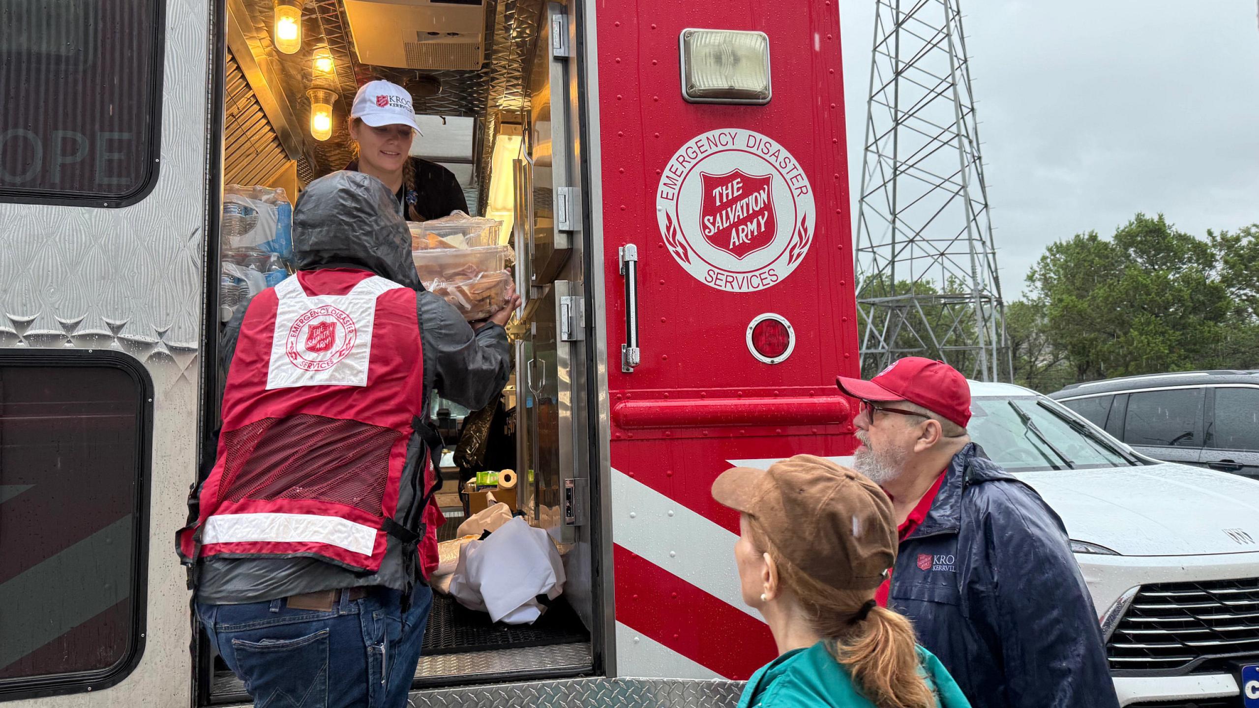 Volunteers unload supplies from a Salvation Army emergency vehicle