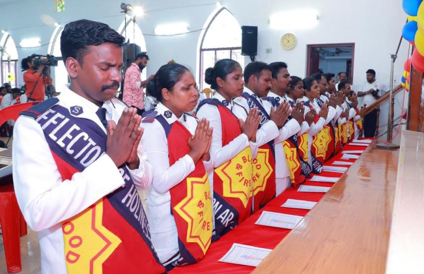Men and women in Salvation Army uniform kneel in prayer