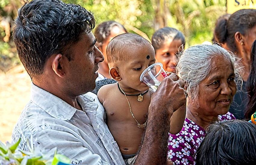 A young child drinks from a Salvation Army cup