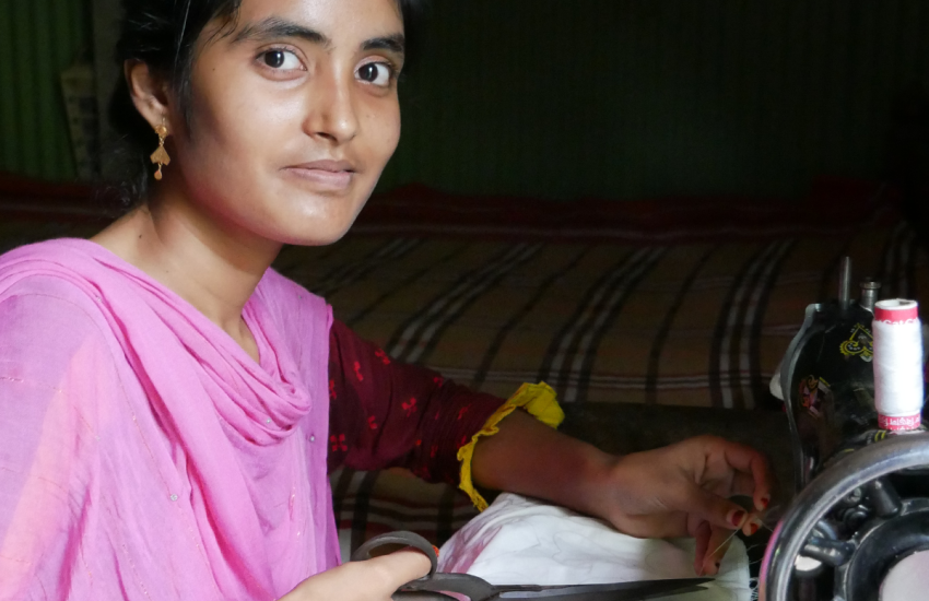 A woman sits at a sewing maching