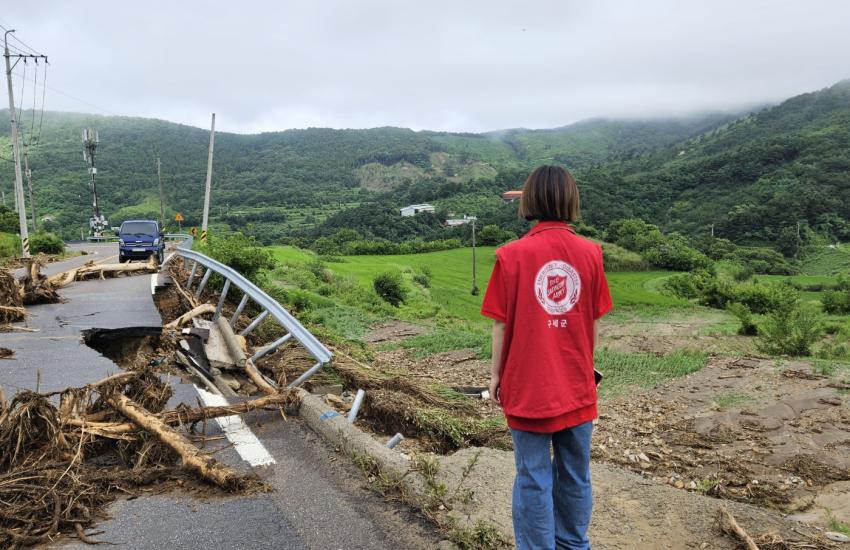 A person in a Salvation Army t-shirt looks out at a flood-damaged road
