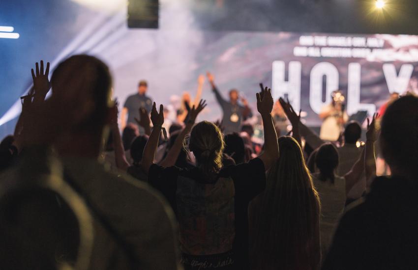 Young people raise their hands in worship
