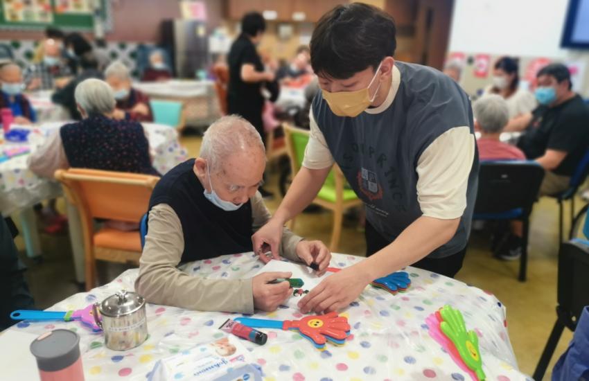 A carer assists a male resident in a care facility in Macau