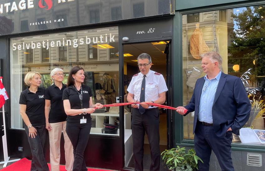 A Salvation Army officer cuts the ribbon in front on the shop
