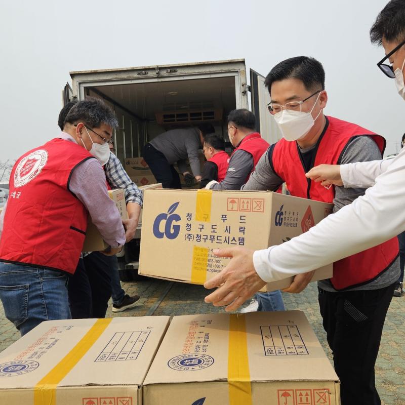 A group of men in red Salvation Army jackets pack boxes into a van