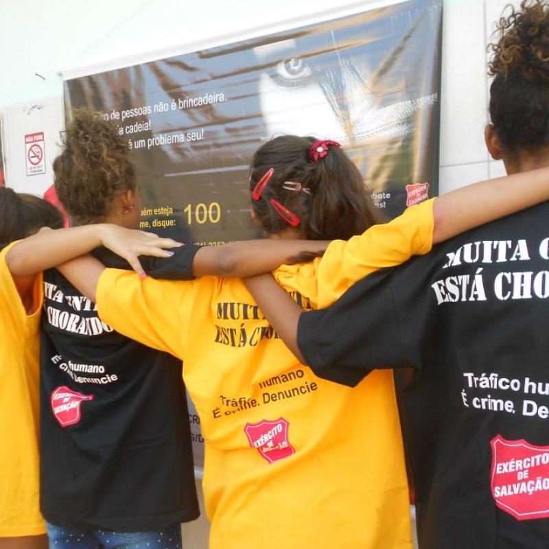 Four young women wear t-shirts with the message 'muita gente está chorando'