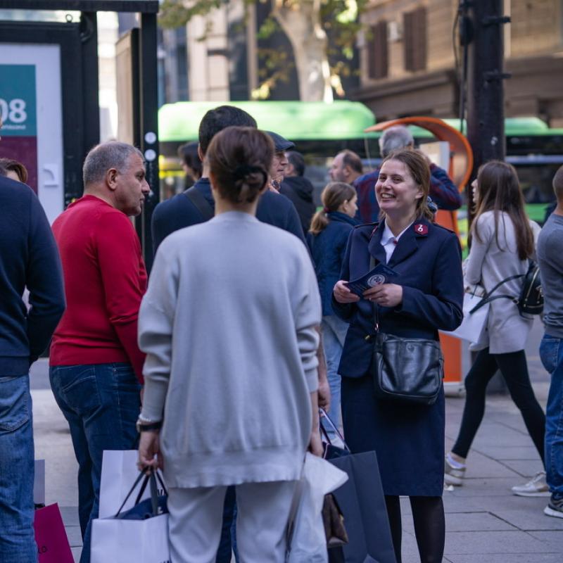 A woman in Salvation Army uniform speaks to people in a busy street