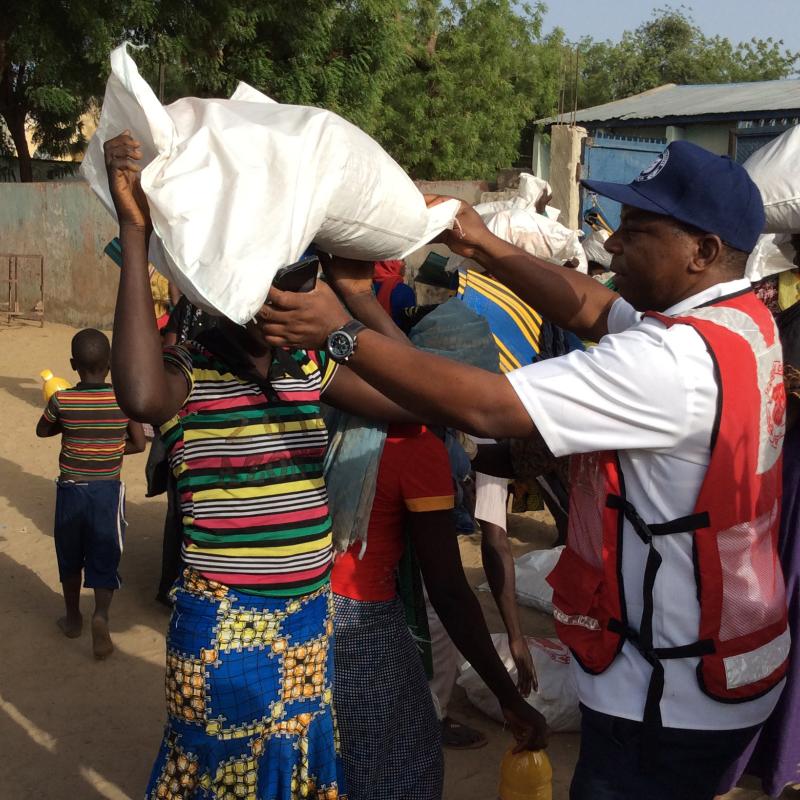 A man wearing a Salvation Army jacket helps a woman with a bag of supplies