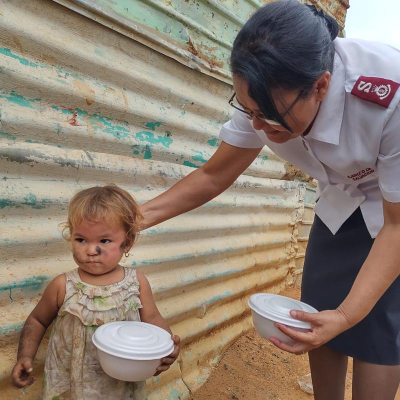 A woman in Salvation Army uniform speaks to a young child