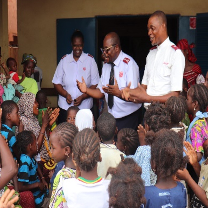 Salvation Army officers speak to a crowd of women and children