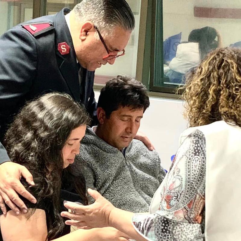 Two people in Salvation Army clothes pray with a couple