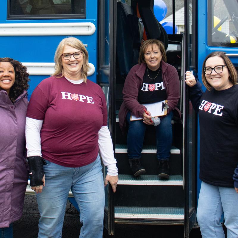 Women wearing Salvation Army t-shirts in front of a bus